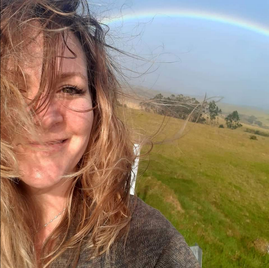 a photo of Holly Smee, in Hawaii, smiling under a rainbow