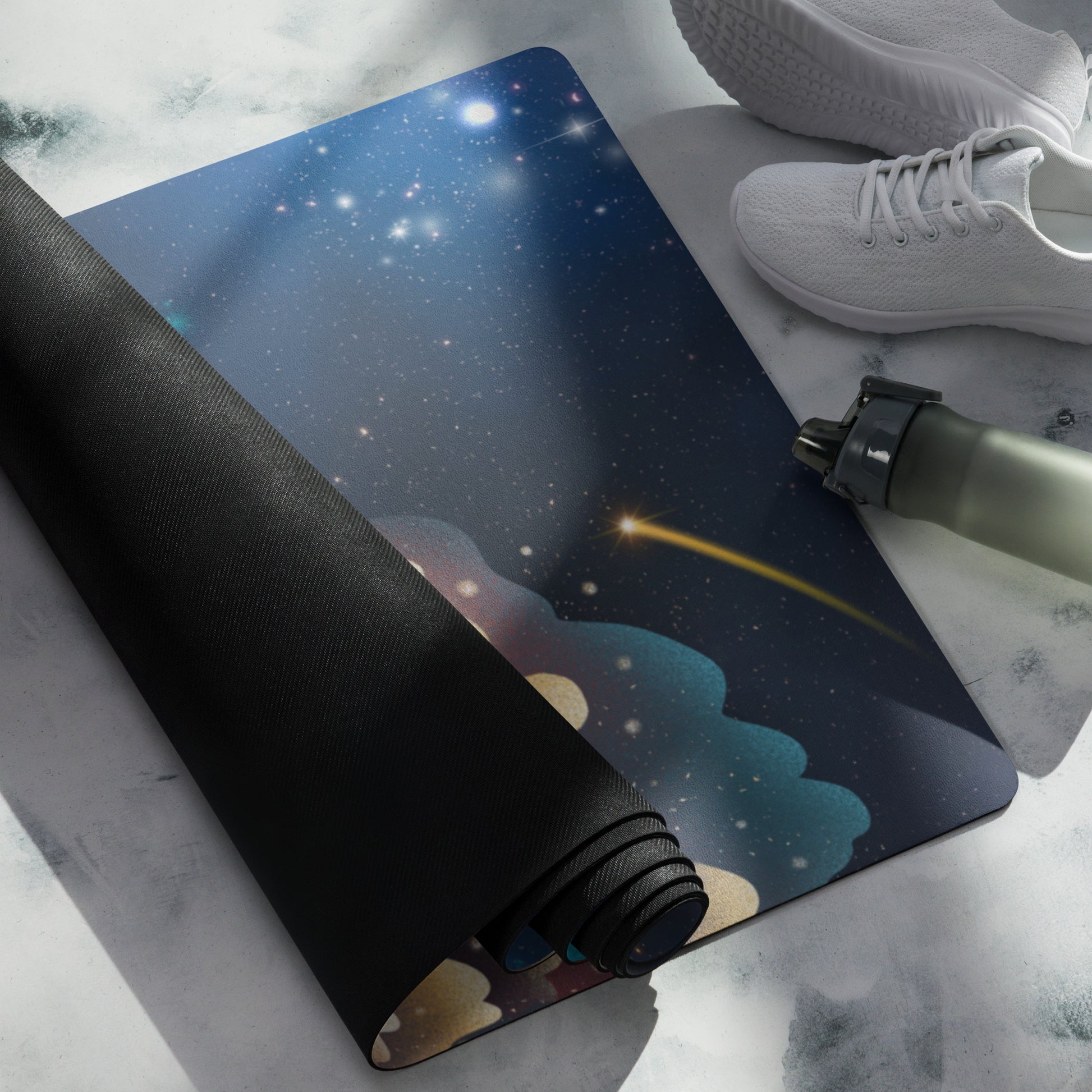 A yoga mat with a celestial or galaxy-themed design, featuring stars and a comet, rolled out next to a black rolled-up mat with a shoe and a bottle placed on top.