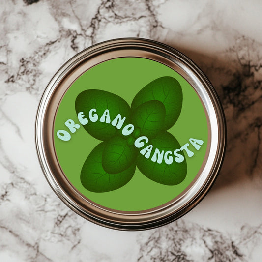 A round sticker with a green background featuring the text 'OREGANO GANGSTA' arranged around a cluster of oregano leaves on a marble surface.