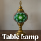 Decorative table lamp with green mosaic design on a wooden surface