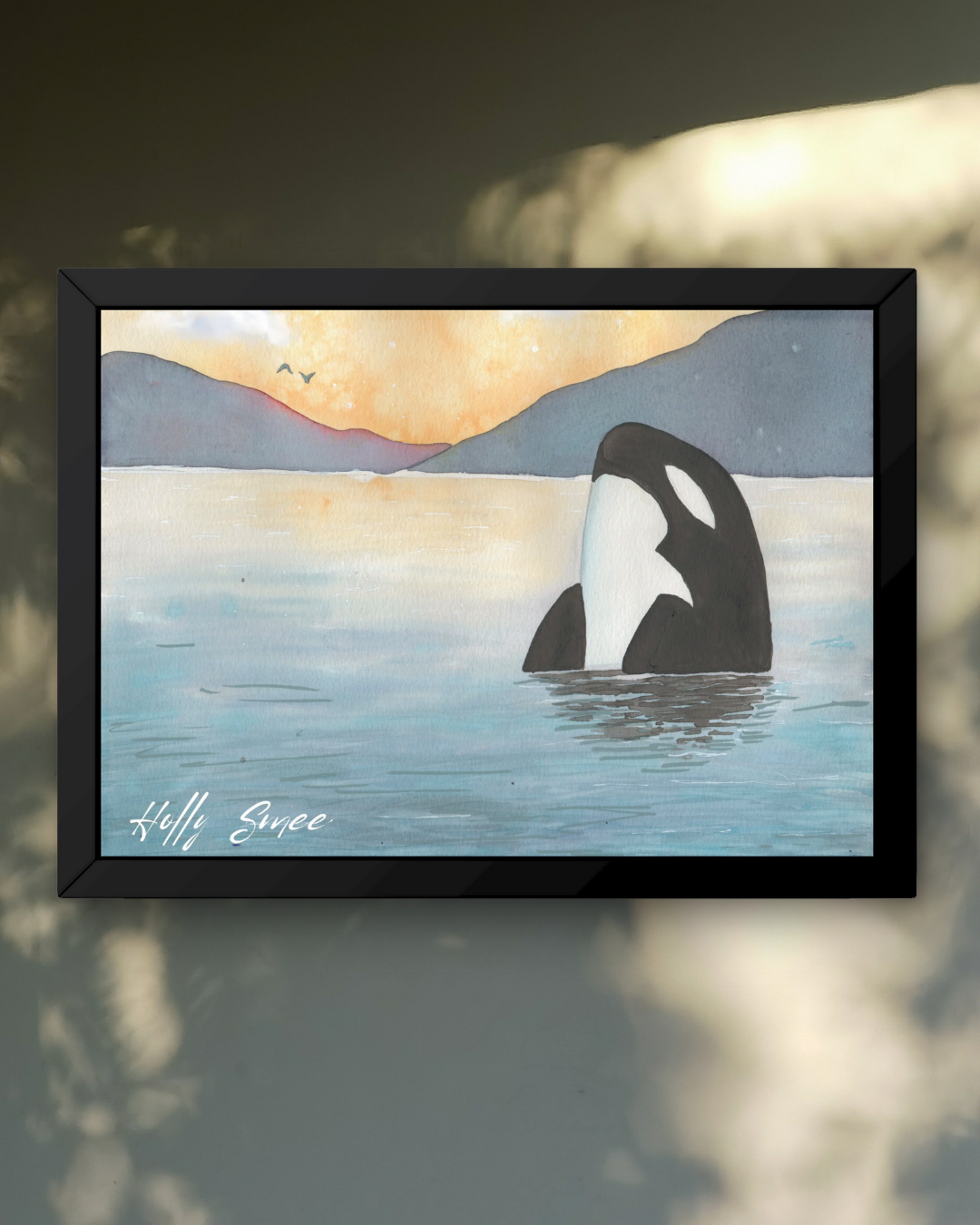Framed artwork of an orca whale in water with mountains and sunset.